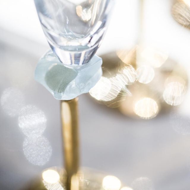 anna tableware designer, tall elegant champagne glass on a hand polished bronze stem, Amar has a piece of light dawn blue glass gem for classy decoration