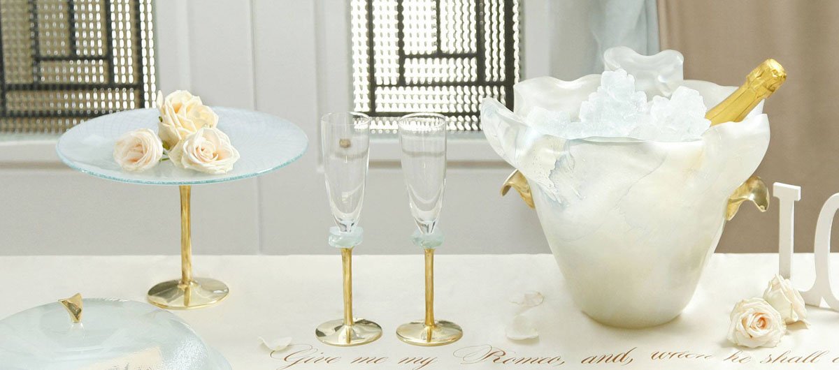 Elegant and romantic table setting including champane bucket, glass dome, champagne glass, cake stand a small glass bowl with a lot of flowers and a Sheakspeare sonnet written on the table cloth
