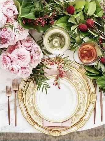 well set table with floral dinnerware with golden cutlery, fresh flowers and wine glasses