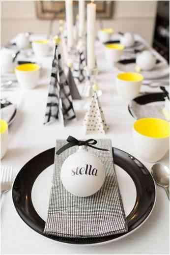 Christmas table setting in minimalistic white and black with yellow elements with customized Christmas toy in white with black ribbon