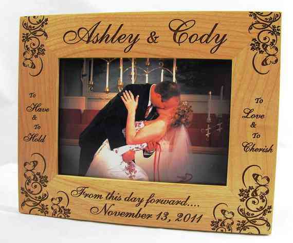 Customized wooden picture frame with the names of Ashley and Cody and their wedding details. In the frame is a picture of the couple kissing on their wedding day.