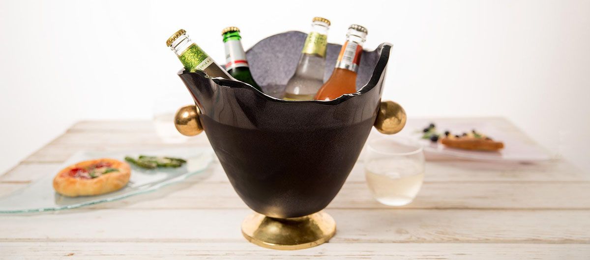 Gala is a gorgeous blue wine ice bucket that sits on a bronze pedestal with handcasted and hand polished bronze handles. gala is presenting 4 different flavoured beers with ice. On the background you can see 2 different