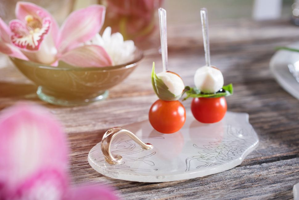 The lovely Elena is a petite canape dish in gentle cream colour patterned with our Perky Chrysanthemum design, with a small shiny bronze handle and is presenting small mozarella and cherry tomatoes bites as part of a Portsea Polo themed table setting