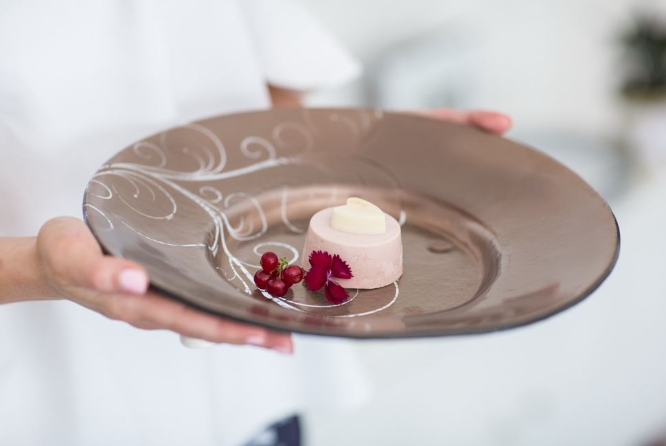 Woman's hands holding large brown valentine plate with small heartshaped dessert in it
