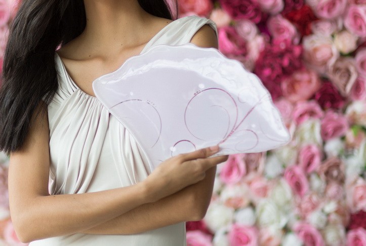 Woman's hands holding holding fan-shaped pink plates as if she is holding a fan
