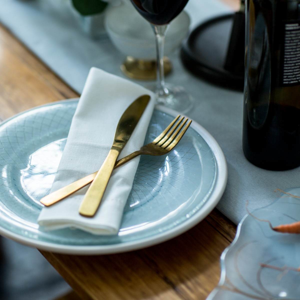 ight blue dinner plate with gold knife and fork on a table with a blue table runner