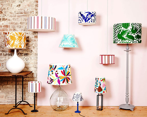Different lamps with colourful mismatched lampshades in front of a pink wall 
