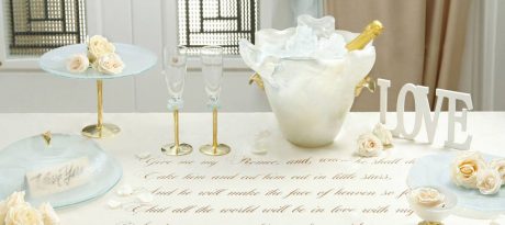 Elegant and romantic table setting including champane bucket, glass dome, champagne glass, cake stand a small glass bowl with a lot of flowers and a Sheakspeare sonnet written on the table cloth