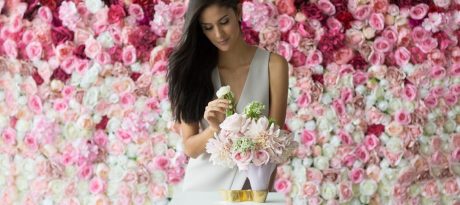 A woman arranging a bouquet in a beautiful pink vase